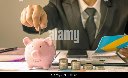 Gros plan sur une femme d'affaires qui met de l'argent dans une banque de cochon, des idées d'économie d'argent et d'économiser de l'argent pour l'avenir. Banque D'Images