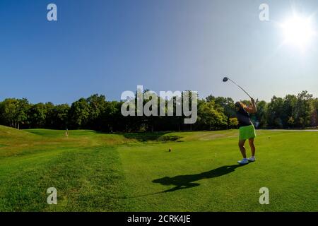 golfeur femelle à gros plan sur un parcours de golf ensoleillé, pilote de balancement activé raccord en t. Banque D'Images