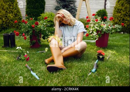 Femme fatiguée assise sur l'herbe dans le jardin Banque D'Images