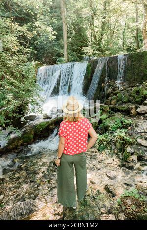 Jeune femme explorateur de la nature debout devant la cascade Banque D'Images