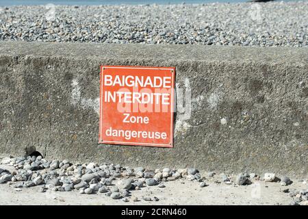 Signe sur une plage avec écrit sur elle en français 'baignade interdite, zone dangereuse' Banque D'Images