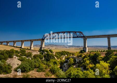 Un viaduc traverse un ravin à Basilicate, en Italie. La route surélevée, au-dessus des champs et des collines vertes du sud de l'Italie. Végétation et arbres au bot Banque D'Images