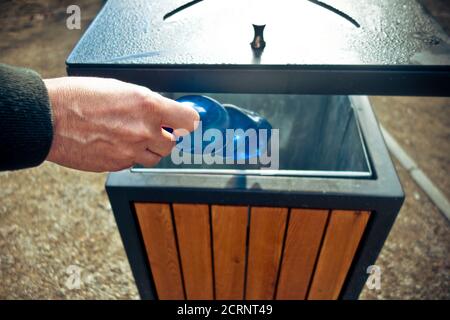 mettre à la main une bouteille en plastique dans un conteneur de déchets publics Banque D'Images