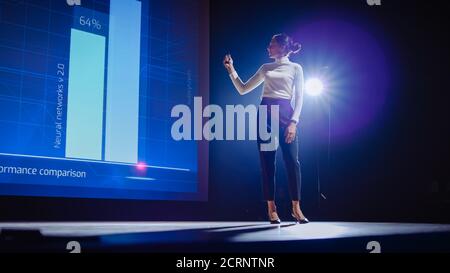 Le haut-parleur Femme sur scène présente un produit technologique, utilise la télécommande pour la présentation, affiche des infographies, des statistiques d'animation Banque D'Images