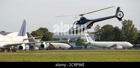 Aéroport de Cotswold, Cirencester, Gloucestershire, Royaume-Uni. 2020. Hélicoptère volant à proximité de gros avions à réaction qui attendent la mise au rebut et le recyclage Banque D'Images