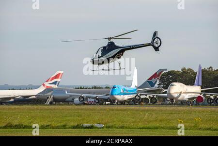 Aéroport de Cotswold, Cirencester, Gloucestershire, Royaume-Uni. 2020. Hélicoptère volant à proximité de gros avions à réaction qui attendent la mise au rebut et le recyclage Banque D'Images