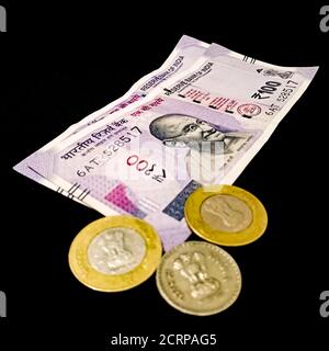 Monnaie indienne cinq cents 500 roupies note avec trois pièces de 10 roupies isolées sur fond noir à des fins de marketing financier. Banque D'Images