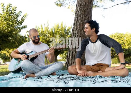 Deux amis qui s'amusent et jouent de la guitare dans le parc Banque D'Images