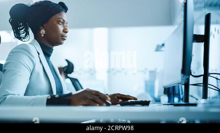 Belle femme ingénieure travaillant sur un ordinateur personnel dans l'usine industrielle de haute technologie. Bureau occupé dans une usine. Vue latérale Portrait Banque D'Images