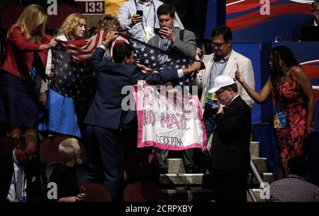Supporters of Republican U.S. presidential nominee Donald Trump attempt to obscure a protestor from the activist group Code Pink who is holding an anti-racism and anti-hate banner as she interrupts the proceedings during the second day of the Republican National Convention in Cleveland, Ohio, U.S. July 19, 2016. REUTERS/Mike Segar