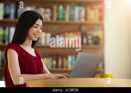 Femme asiatique souriante étudiante se préparant pour les cours avec un ordinateur portable Café Banque D'Images
