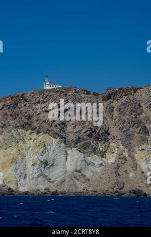 Falaise et phare au sud de l'île de Thira dans les îles grecques, par une journée claire et ensoleillée avec un ciel bleu et lumineux. Akrotiri, Santorin, Grèce. Akroti Banque D'Images