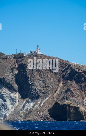 Falaise et phare au sud de l'île de Thira dans les îles grecques, par une journée claire et ensoleillée avec un ciel bleu et lumineux. Akrotiri, Santorin, Grèce. Akroti Banque D'Images