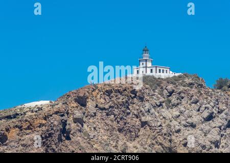 Falaise et phare au sud de l'île de Thira dans les îles grecques, par une journée claire et ensoleillée avec un ciel bleu et lumineux. Akrotiri, Santorin, Grèce. Akroti Banque D'Images