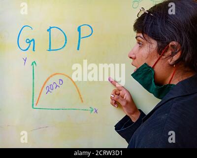 DISTRICT KATNI, INDE - 17 MAI 2020: Un enseignant indien a affiché le produit intérieur brut PIB déclin graphique corona concepts de temps sur le tableau de couleur claire W Banque D'Images