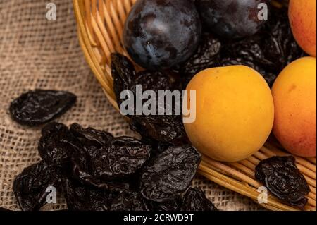 Abricots mûrs, prunes noires juteuses et pruneaux séchés dans un panier en osier. Gros plan. Récolte d'automne Banque D'Images