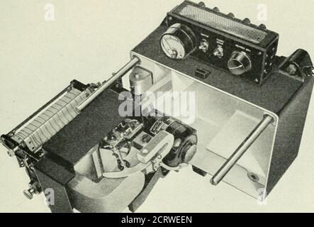 . Le journal technique du système Bell . l'écart fait que le mouvement angulaire de la bobine est approximativement proportionnel au changement actuel exprimé en db. La figure 4 est une vue du système mobile et du mécanisme d'enregistrement hors du boîtier et montre la bobine mobile et le grand magnétassocié à celui-ci. Il est à noter qu'un petit aimant est monté, ENREGISTRANT LE SYSTÈME de MESURE TR^iNSMISSION 27 près du grand. Cet aimant induit des courants de Foucault dans une vanequi est attachée à une extension du pointeur, agissant ainsi comme un abarâteau pour contrôler l'amortissement du système mobile. L'ordinaryme Banque D'Images