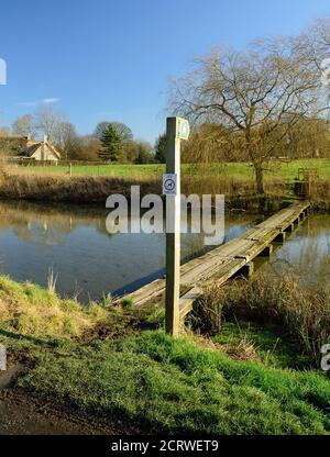 Une passerelle de vieilles traverses de chemin de fer traversant l'étang du moulin dans le petit village de Sherrington dans le Wiltshire. Banque D'Images