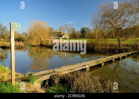 Une passerelle de vieilles traverses de chemin de fer traversant l'étang du moulin dans le petit village de Sherrington dans le Wiltshire. Banque D'Images