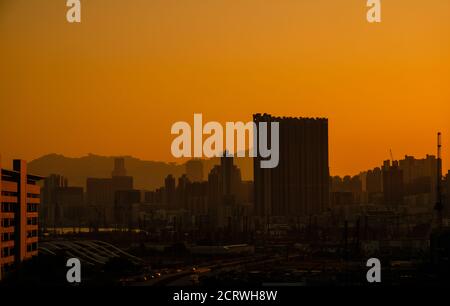 Ville, gratte-ciel, grues de construction et coucher du soleil à Hong Kong Banque D'Images