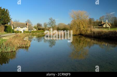 Un cottage de chaume à côté de l'étang du moulin dans le petit village de Sherrington dans le Wiltshire. Banque D'Images