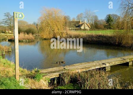 Une passerelle de vieilles traverses de chemin de fer traversant l'étang du moulin dans le petit village de Sherrington dans le Wiltshire. Banque D'Images