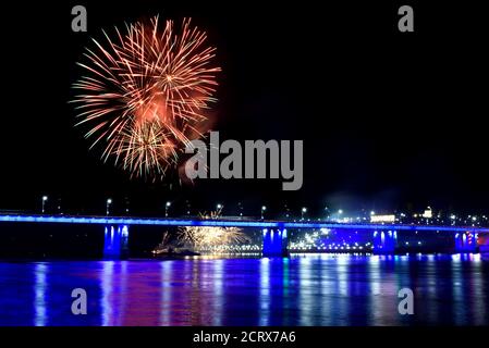 Feux d'artifice festifs colorés, saluez le pont avec un éclairage bleu, des remblais et des reflets dans l'eau de la rivière Banque D'Images