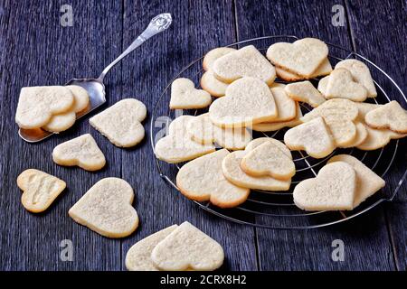 biscuits sablés en forme de coeur sur un panier de refroidissement en fil de fer sur une table en bois sombre, vue horizontale d'en haut Banque D'Images