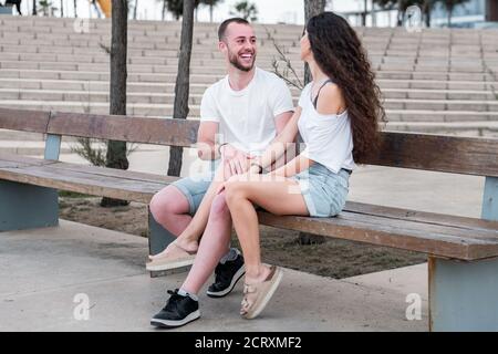 Jeune couple caucasien joyeux assis sur un banc Banque D'Images
