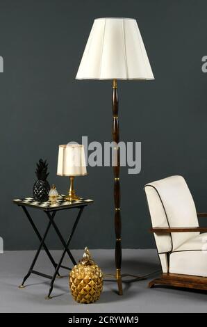 Décoration intérieure, mobilier vintage élégant comprenant une lampe de plancher en bois, un fauteuil et une lampe de table sur une table à carreaux avec abat-jour couleur crème Banque D'Images