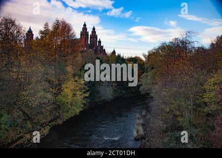 Glasgow / Écosse - 13 novembre 2013 : vue sur la galerie d'art et le musée Kelvingrove à travers l'eau sombre et les arbres de la rivière Kelvin. À la lumière du coucher du soleil. Banque D'Images