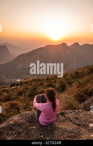 Belle vue sur une femme de randonnée en admirant le coucher de soleil depuis le sommet de la montagne, parc national de Três Picos, Rio de Janeiro, Brésil Banque D'Images