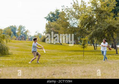 adolescent tenant une batte de softball et jouant au baseball avec son père dans le parc vert Banque D'Images