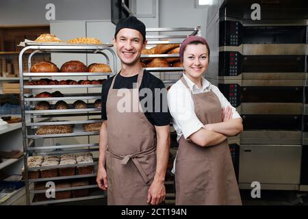 Couple de fiers travailleurs, hommes et femmes posant pour une photo dans une cuisine de boulangerie Banque D'Images