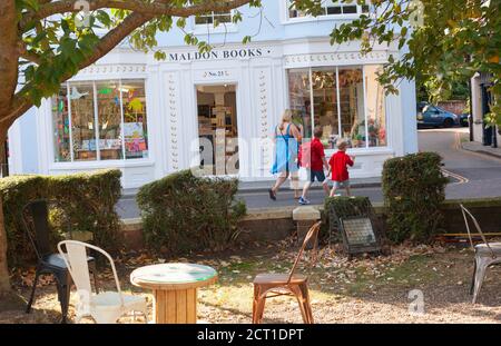 Vue latérale de deux enfants en uniforme d'école rouge vif et jeune femme marchant à côté de la boutique Maldon Books. Maldon, Essex, Grande-Bretagne Banque D'Images