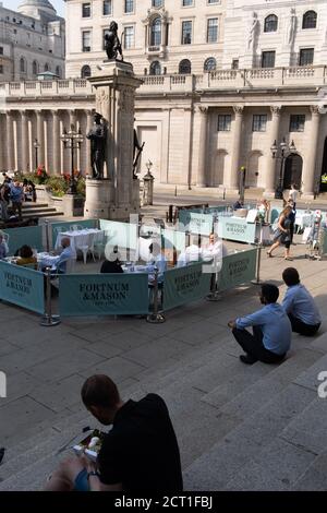 Les Diners et les buveurs se trouvent à l'intérieur des barrières de la rue où Fortnum & Mason a installé un bar-restaurant en plein air devant la Royal Exchange à la Bank, dans la City de Londres, pendant la pandémie du coronavirus, le 9 septembre 2020, à Londres, en Angleterre. Banque D'Images