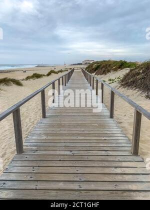 Promenade en bois traversant les dunes de sable de Costa Nova, Portugal, avec l'océan en arrière-plan Banque D'Images