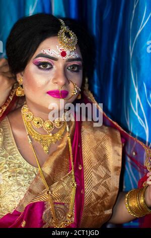 Portrait d'un adorable modèle indien à l'aspect de la mariée avec bijoux en or épais et sari rouge Banque D'Images