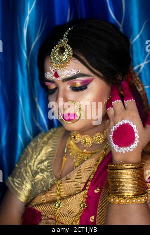 Portrait d'un adorable modèle indien à l'aspect de la mariée avec bijoux en or épais et sari rouge Banque D'Images