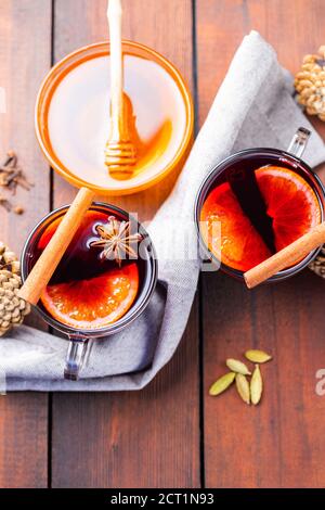 Vin chaud et miel sur fond de bois. Deux tasses de vin chaud d'automne et d'épices. Boisson chaude de Noël dans un style rustique Banque D'Images