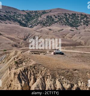 Un véhicule tout-terrain se tient près de la tente sur une surface plane au milieu des collines. Magnifique paysage de montagne Banque D'Images