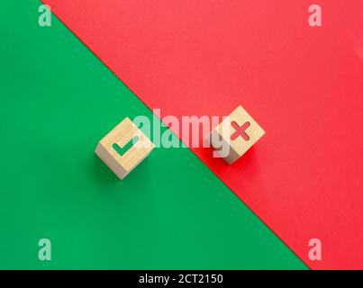 Quelques cubes de bois avec des icônes de vérification et de mauvaise chanson sur un fond vert et rouge. Concept correct et incorrect. Banque D'Images