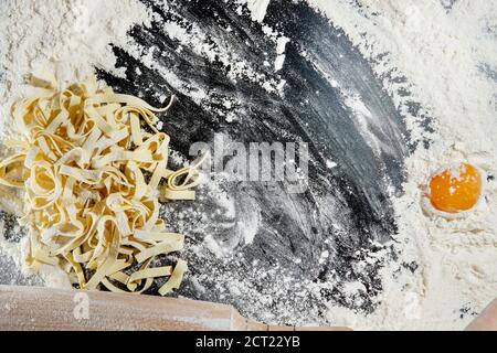 flat lay with rolling pin and ingrédients for italian pasta disposés sur un plan d'examen noir Banque D'Images