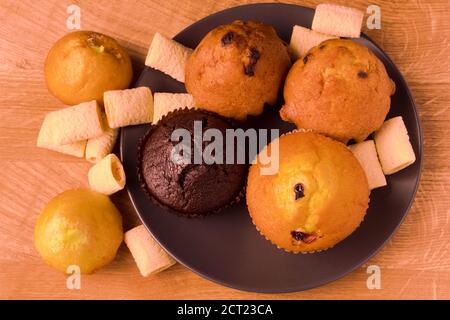 Petits gâteaux et pop-corn dans une assiette noire sur un bois carte Banque D'Images