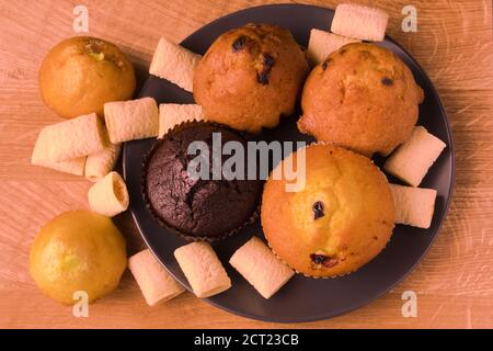 Petits gâteaux et pop-corn dans une assiette noire sur un bois carte Banque D'Images