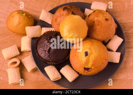 Petits gâteaux et pop-corn dans une assiette noire sur un bois carte Banque D'Images