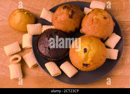Petits gâteaux et pop-corn dans une assiette noire sur un bois carte Banque D'Images