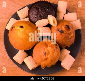 Petits gâteaux et pop-corn dans une assiette noire sur un bois carte Banque D'Images
