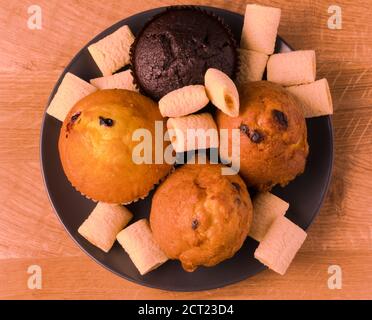 Petits gâteaux et pop-corn dans une assiette noire sur un bois carte Banque D'Images