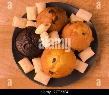 Petits gâteaux et pop-corn dans une assiette noire sur un bois carte Banque D'Images